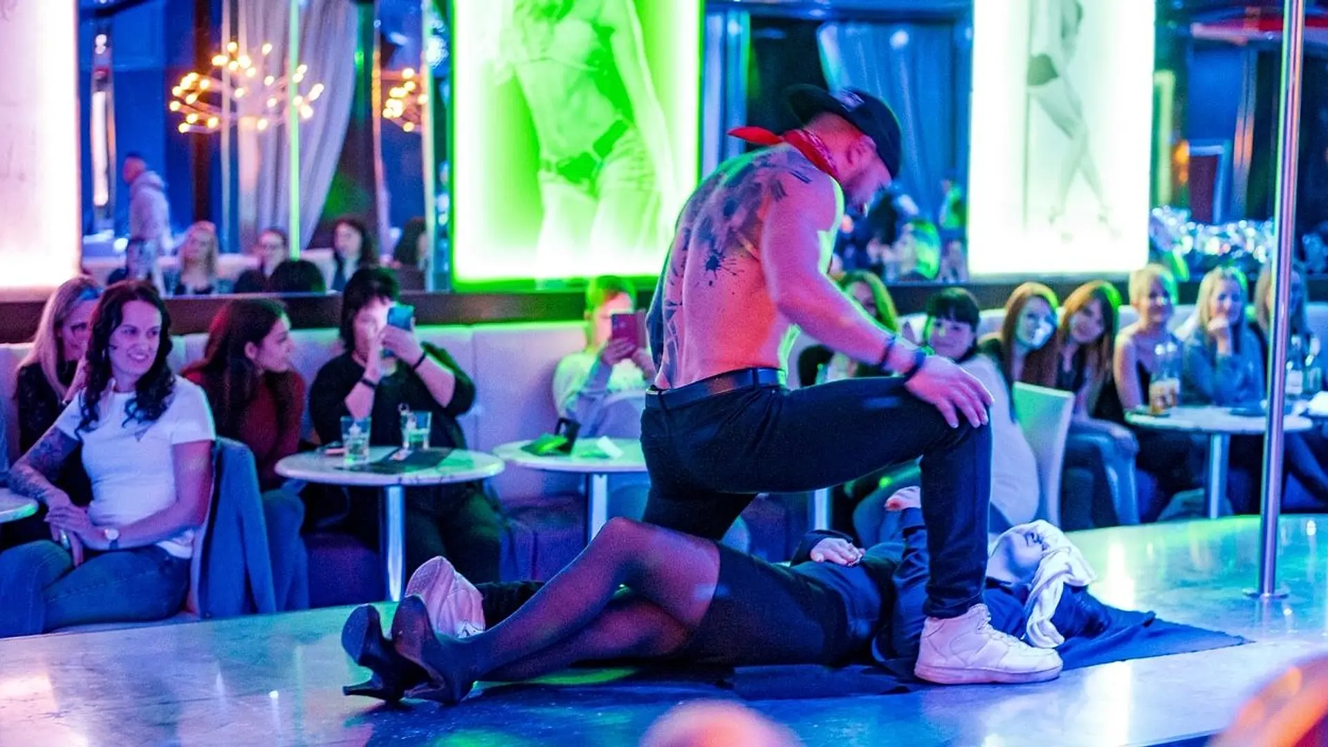 Stripperin an der Stange auf einer Bühne mit roten Stiefeln