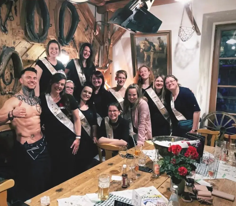 Gäste mit Schärpen am Tisch beim Dinner mit Stripper