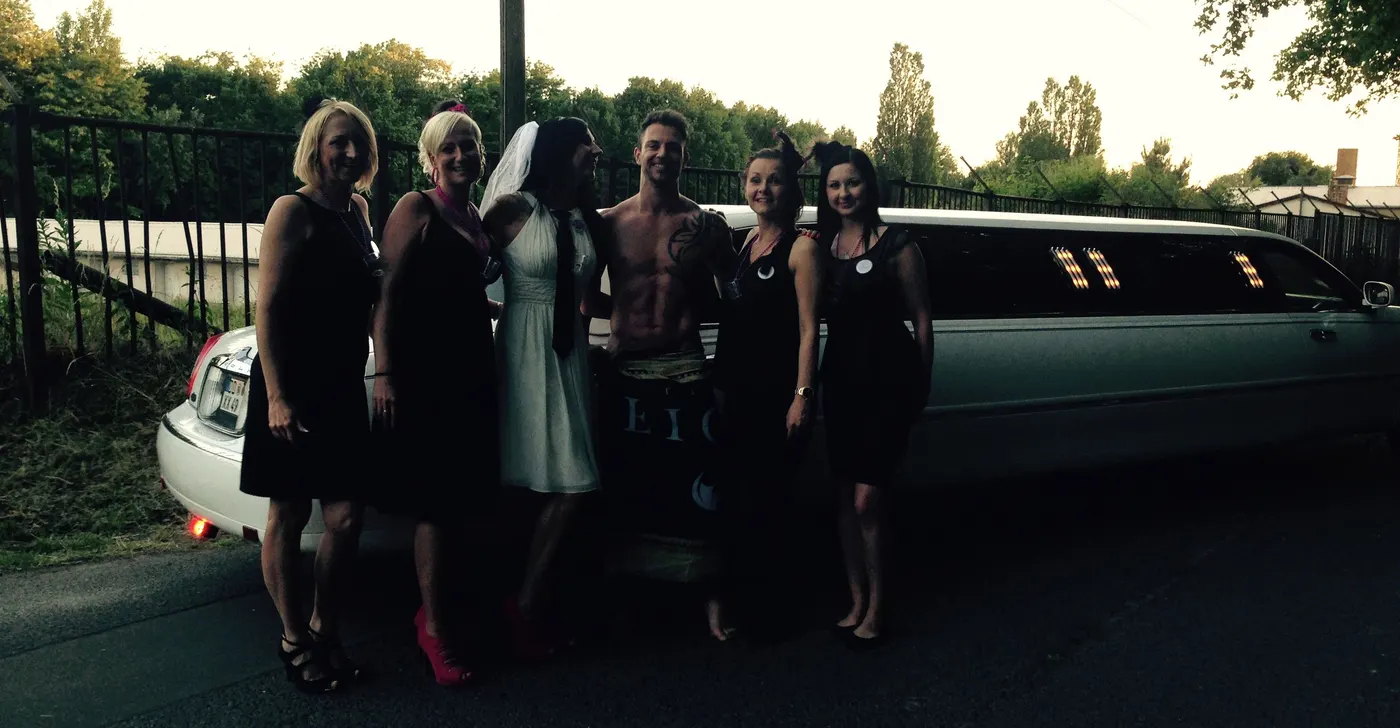 Gruppe mit Stripper vor der Limousine am Abend
