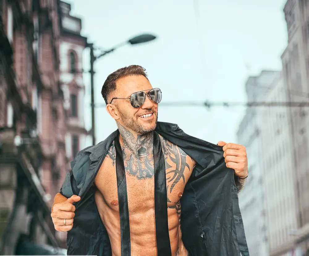 Stripper im offenen Hemd vor einer Altstadtkulisse